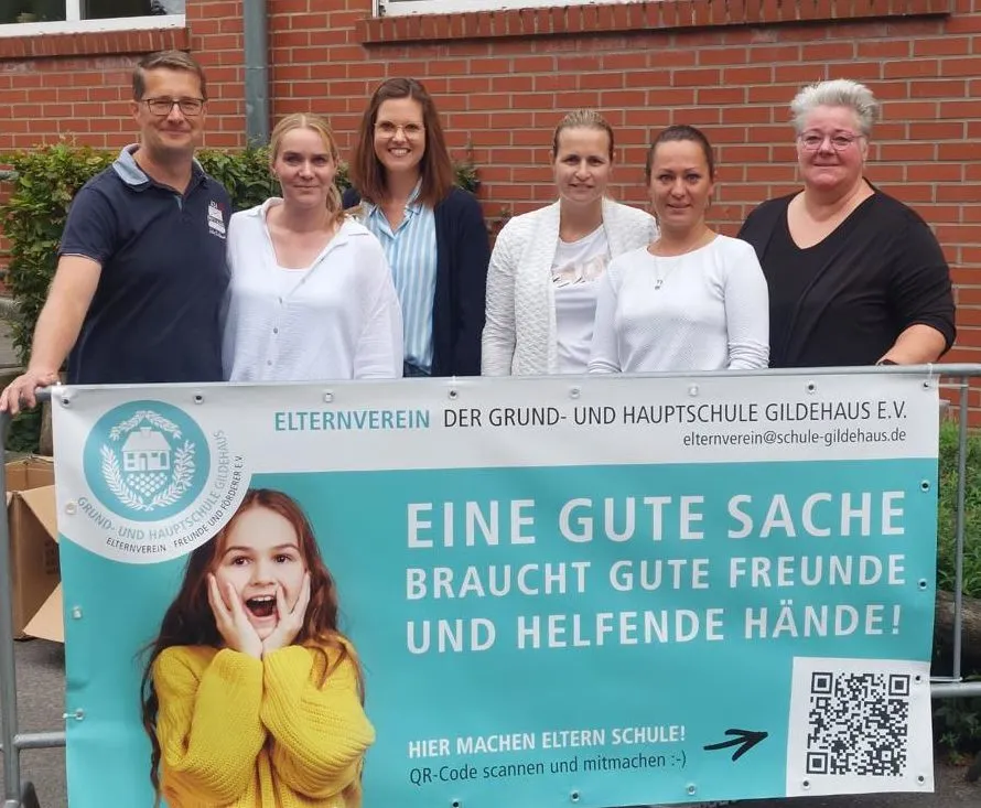 Sechs Mitglieder des Elternvereins stehen hinter einem Banner mit der Aufschrift „Eine gute Sache braucht gute Freunde und helfende Hände!“